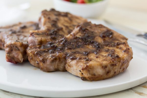 pork chops on a white place with raspberry jalapeno glaze