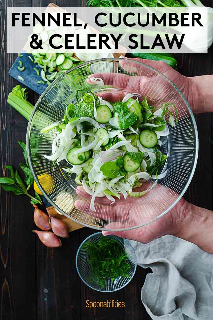 two hands holding a clear bowl with Fennel, cucumber & celery slaw