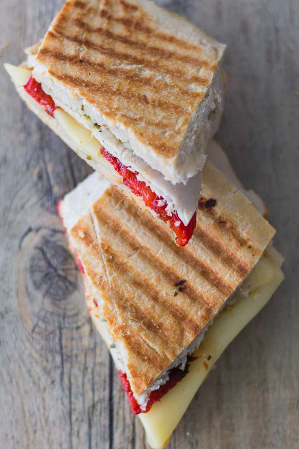 Smoked Turkey Artichoke Panini sandwich tastes as good as it looks. Made with ciabatta sandwich roll spread with Artichoke Parmesan Tapenade, stacked with roasted red pepper, smoked turkey and topped with mozzarella cheese. Spoonabilities.com