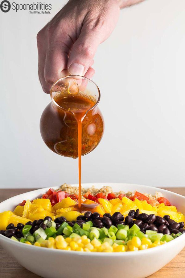 Pouring Santa Fe Salad Dressing on a rainbow salad