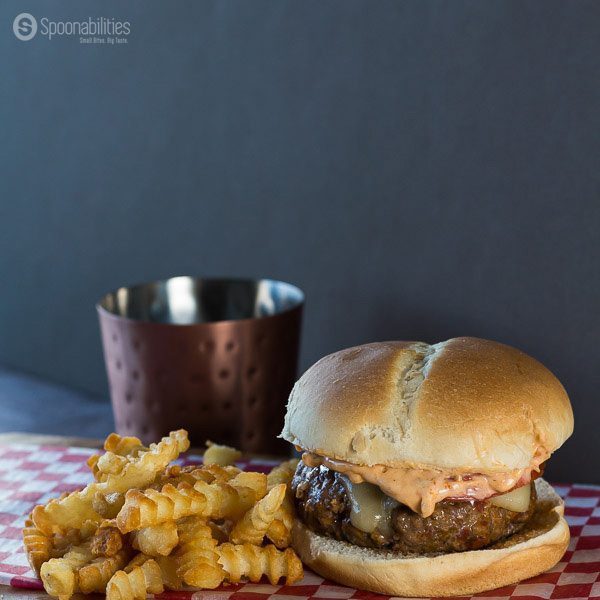 Spicy burger next to handful of crinkle fries