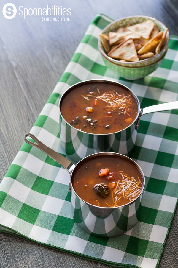 Two pots of Hearty Vegetable Soup sitting on a green and white checked tablecloth