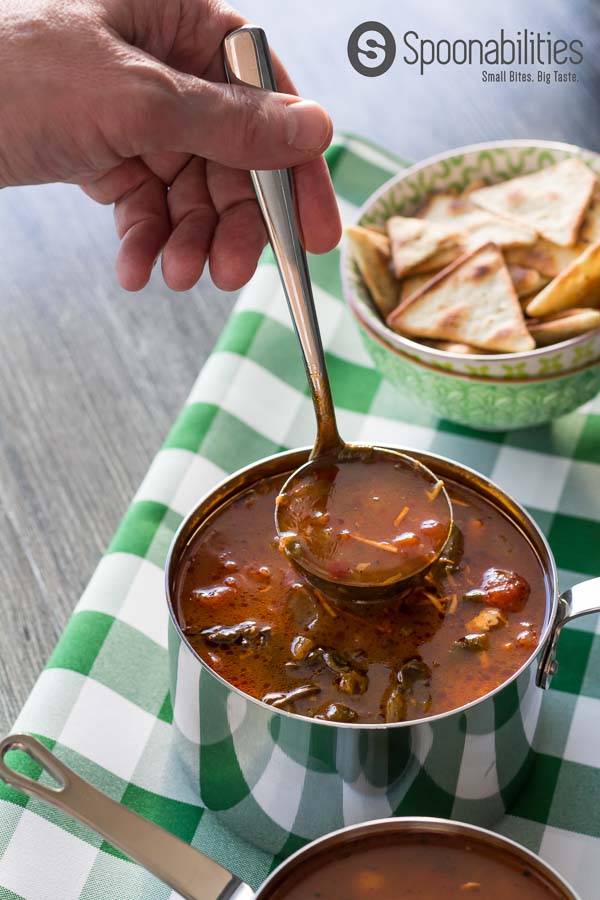 Full ladel of Hearty Vegetable Soup hovering over a full pot of soup