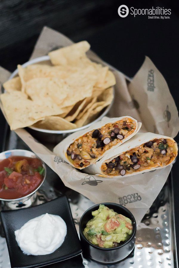 Two halves of Southwestern Chicken Wraps in a basket with a bowl of tortilla chips