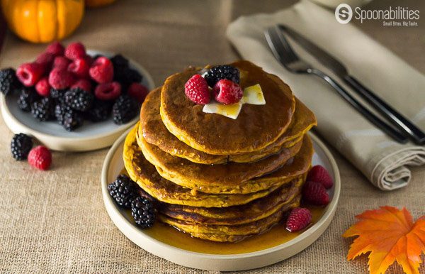 stack of 8 Spiced Pumpkin Pancakes with bowl of blackberries and raspberries in the background