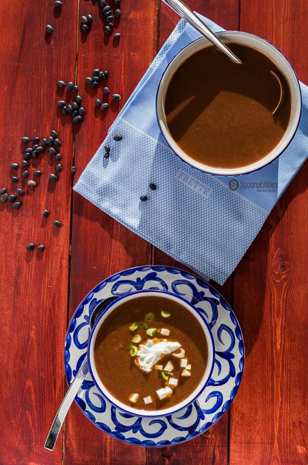 one bowl and one pot of Black Bean Soup on cherry wood board