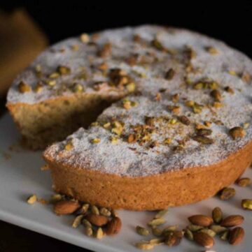 close up photo of Persian Almond Cardamom Pistachio Cake on a white plate. This cake moist and aromatic dessert recipe. Served for Passover using Kosher ingredients.
