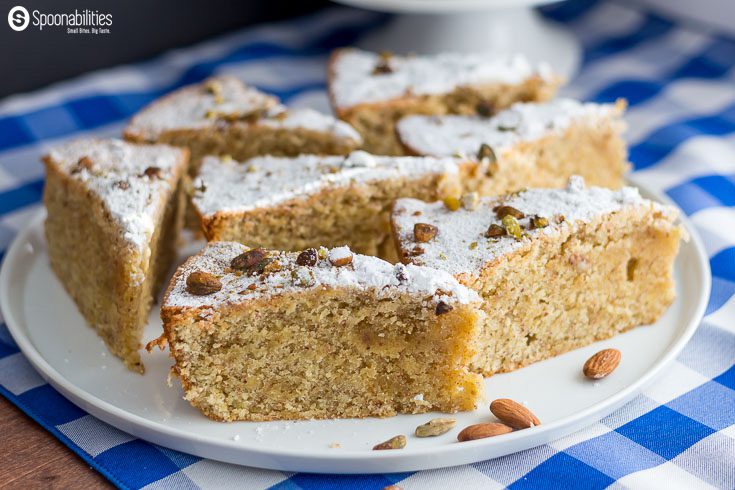 Six pieces of Persian Almond Cardamom Pistachio Cake on a round white platter on top of a checked blue and white napkin. Spoonabilities.com