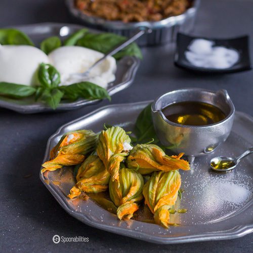 Fresh Stuffed Squash Blossoms is a unique appetizer, filled with creamy burrata and Kalamata olive and oregano spread. Delicious light and easy recipe. Spoonabilities.com