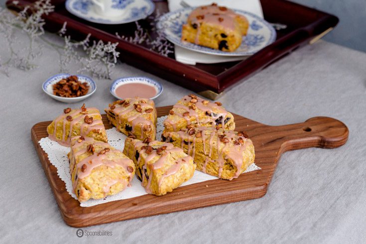 Wooden board with six Cherry Pumpkin Scones with a citrus maple syrup glaze.