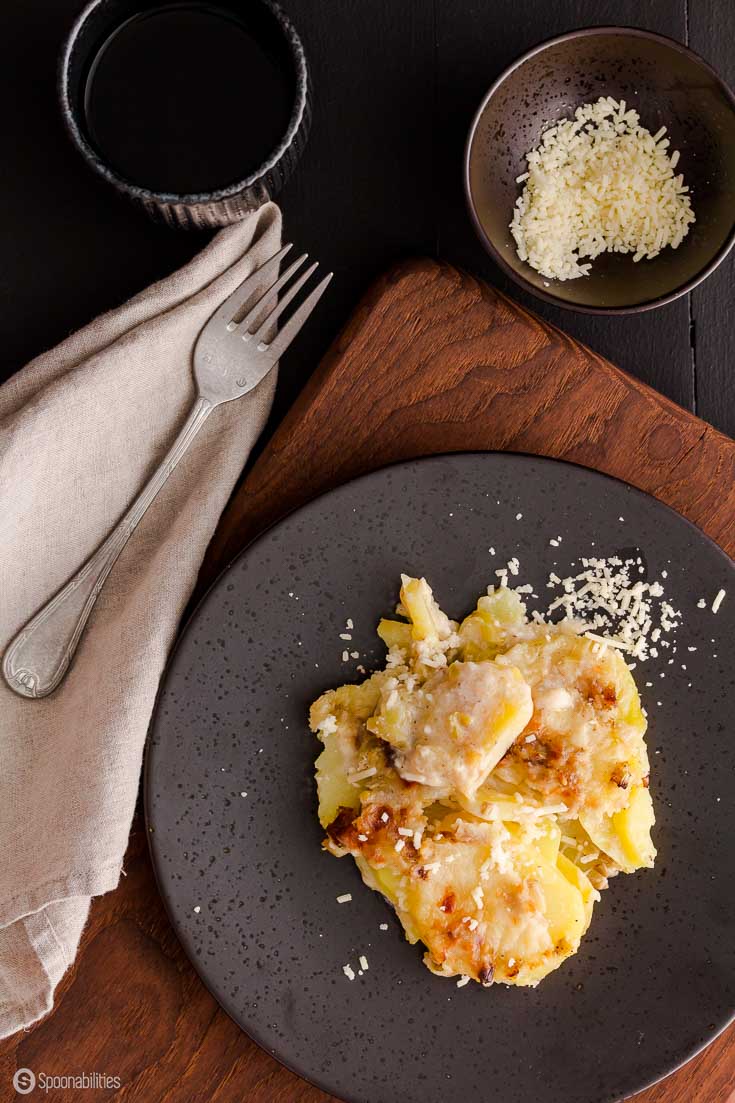 stone place of Potato and Leek gratin next to a napkin and fork on a wood table