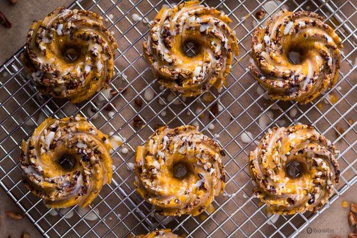 Pumpkin Pecan Cakes with orange glaze are a spongy doughnut-like pastry with crunchy pecan. Perfect for breakfast and dessert. Spoonabilities.com