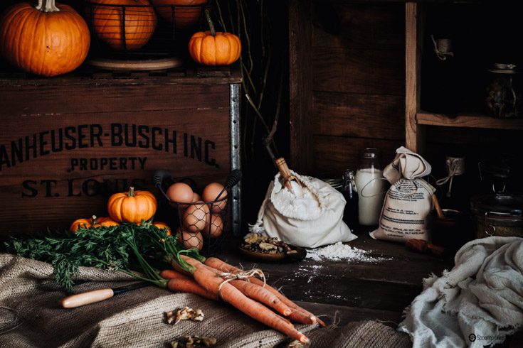 Rustic setting with large, medium and small pumpkins, carrots, natural eggs, flour, and milk