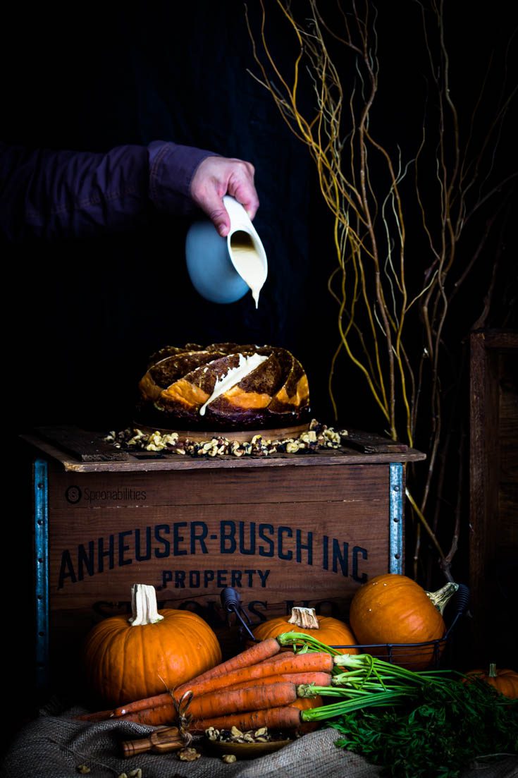 Pouring thick vanilla maple drizzle on a Pumpkin Carrot Bundt Cake
