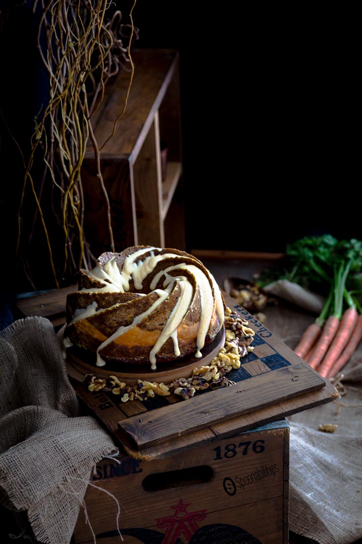 Rustic room setting with a Pumpkin Carrot Bundt Cake on top of a wooden checkerboard.