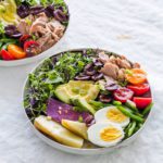 Two bowls of Classic Nicoise Salad on a gray tablecloth
