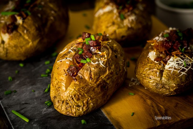 Close up of a baked potato with a perfectly crispy skin and creamy, fluffy interior. Spanish flavor from the aioli, manchego cheese and chorizo & Lomo Iberico. Spoonabilities.com