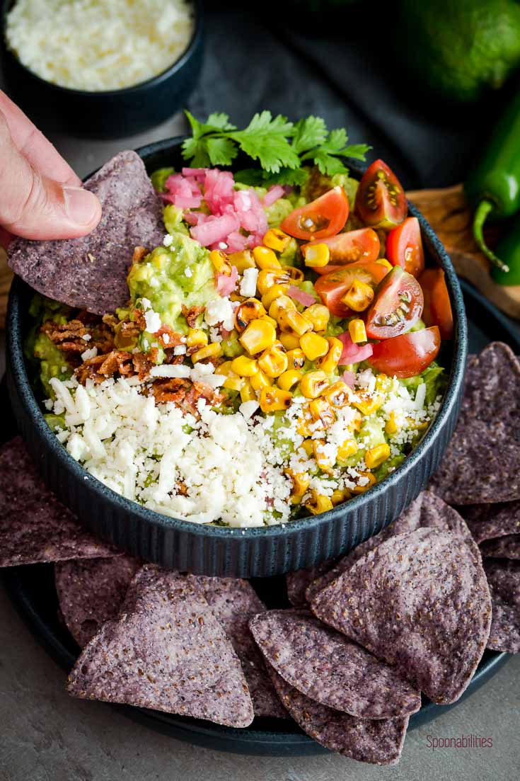 Dipping with a blue corn tortilla at the best guacamole recipe is easy to make. Spoonabilities.com