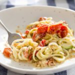 Plate with Zucchini noodles is a healthy summer zoodle recipe with flavorful lemon artichoke pesto, roasted cherry tomatoes & asiago cheese. Spoonabilities.com