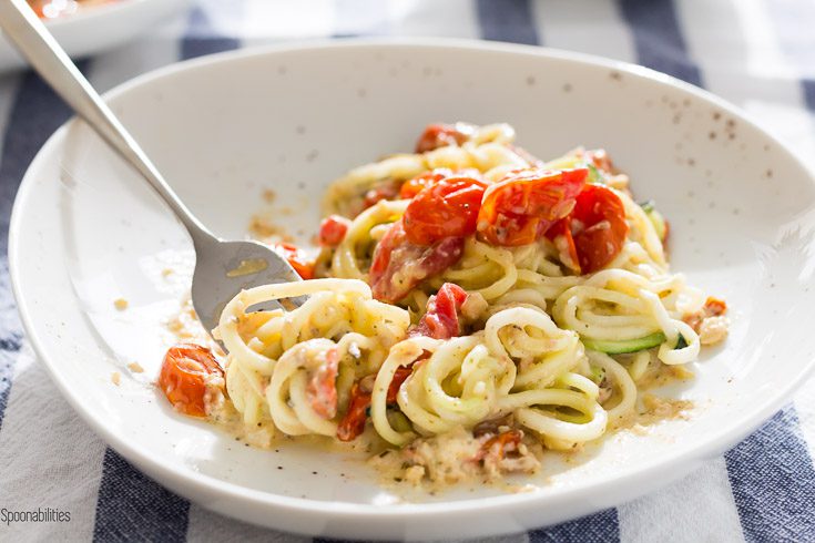 Plate with Zucchini noodles is a healthy summer zoodle recipe with flavorful lemon artichoke pesto, roasted cherry tomatoes & asiago cheese. Spoonabilities.com