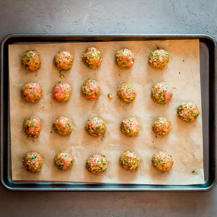 Twenty one spiced lamb meatballs in a lined baking tray. Spoonabilities.com