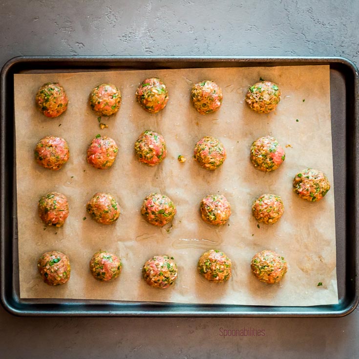 Twenty one spiced lamb meatballs in a lined baking tray. Spoonabilities.com