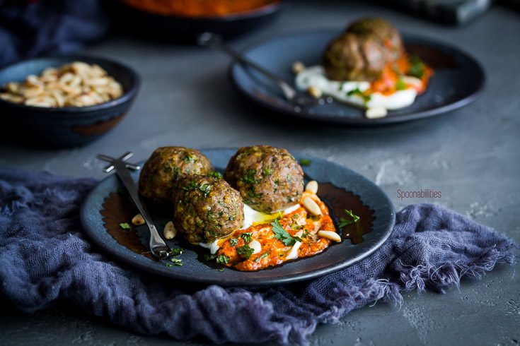 Small plate with three spiced meatballs served as an appetizer on a bed of Greek yogurt and piquillo pepper pesto and garnished with fresh herbs. Excellent appetizer recipe made in 15 minutes and can be made the day before your party. Spoonabilities.com