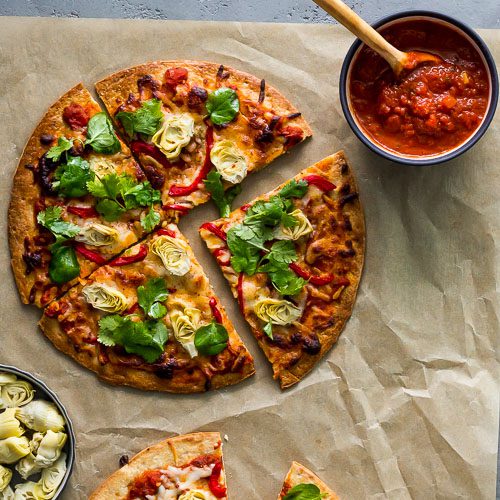 Cauliflower Crust Pizza recipe with Artichokes and Roasted Red Pepper from Flora Fine Foods. Presented with a bowl with pizza sauce and baby artichokes. Spoonabilities.com