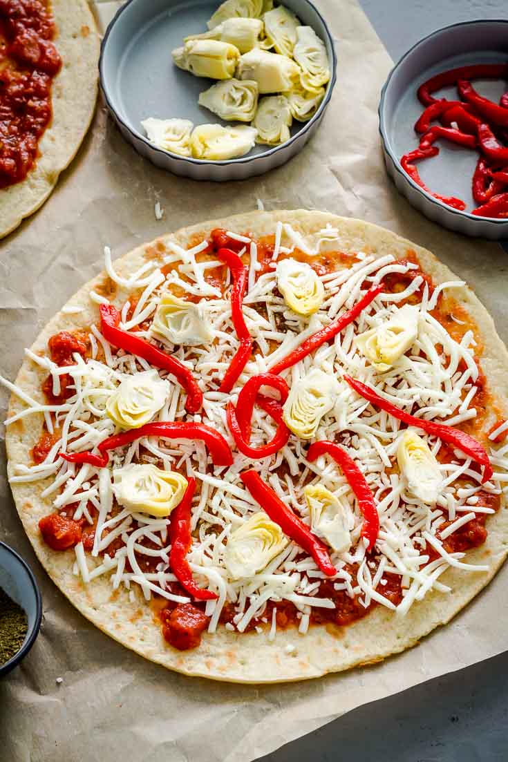 Cauliflower Crust Pizza with Baby Artichokes and Roasted Red Pepper on a parchment paper before go to the oven. Spoonabilities.com