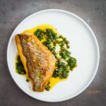 Round white plate with Crispy-Skinned Snapper with Caper Salsa. This salsa has fresh parsley, chili paste, cilantro, olive oil and lemon juice. Spoonabilities.com