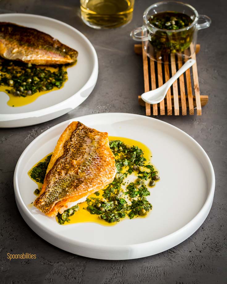 Two white plates with crispy skin snapper with caper salsa. Spoonabilities.com