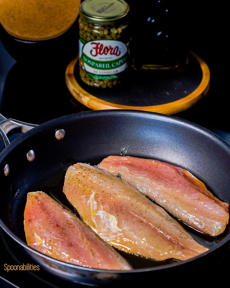 Raw Snapper fish in the fry pan getting the skin crispy. Spoonabilities.com