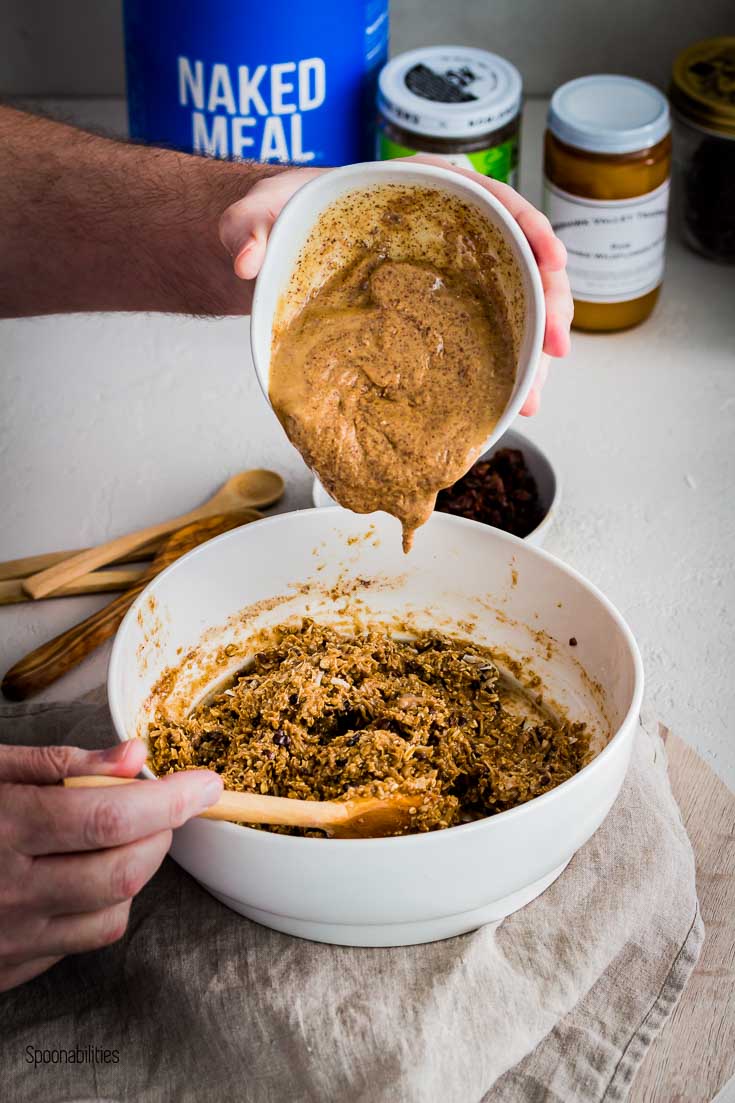Adding almond butter in a round white bowl to the Protein Energy Bites mixture. Spoonabilities.com