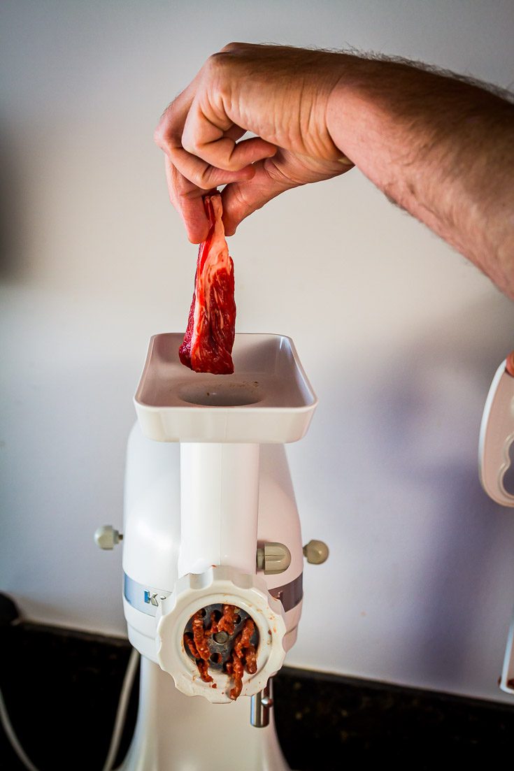 Feeding the strips of meat to the grinding machine. Spoonabilities.com