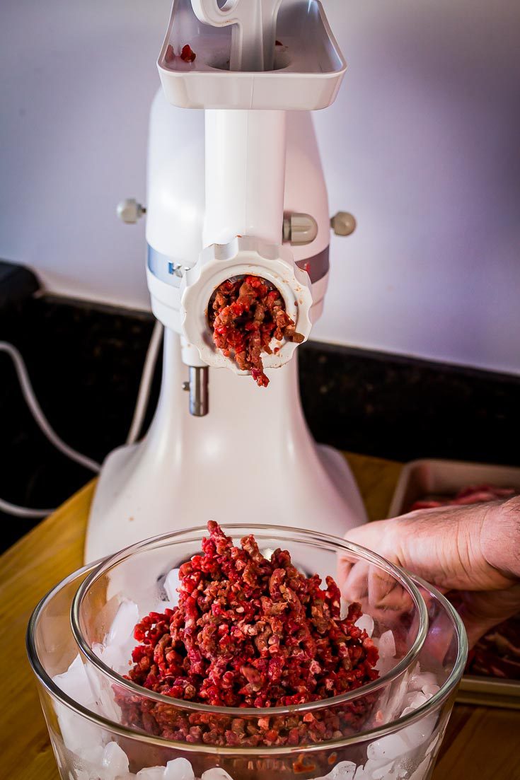 Kitchen aid stand mixer with the food grinder attachment. One large glass bowl with ice and a small glass bowl inside to keep the ground beef cold. Spoonabilities.com