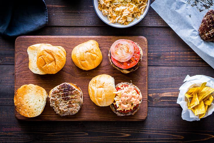 open face Dominican burger in different stages. One with all the elements and topped with the pink sauce, the second with the beef patty, and the last one with the beef patty, tomato and red onion. Spoonabilities.com