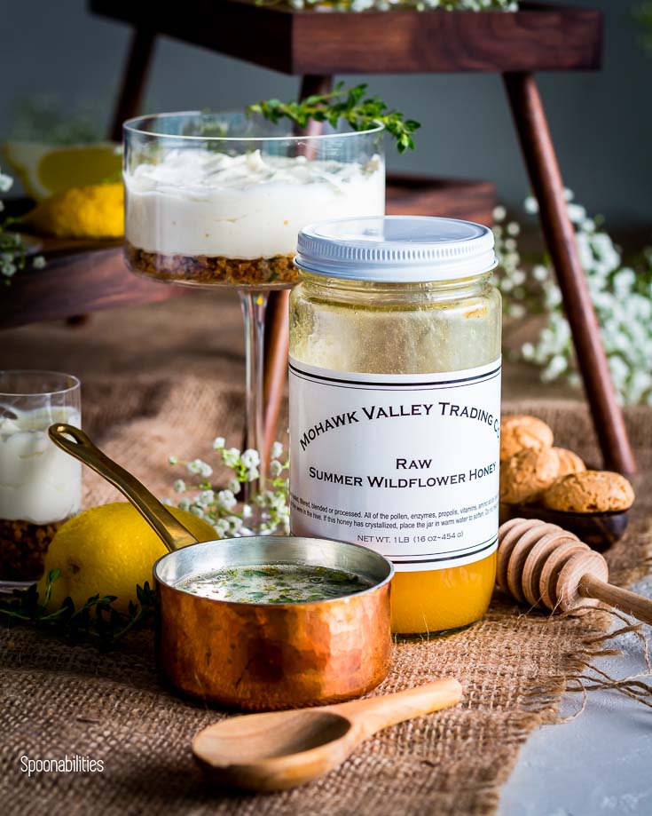 A Jar of Raw Summer Wildflower Honey next to a mini sauce pan with Honey Thyme Drizzle. Spoonabilities.com