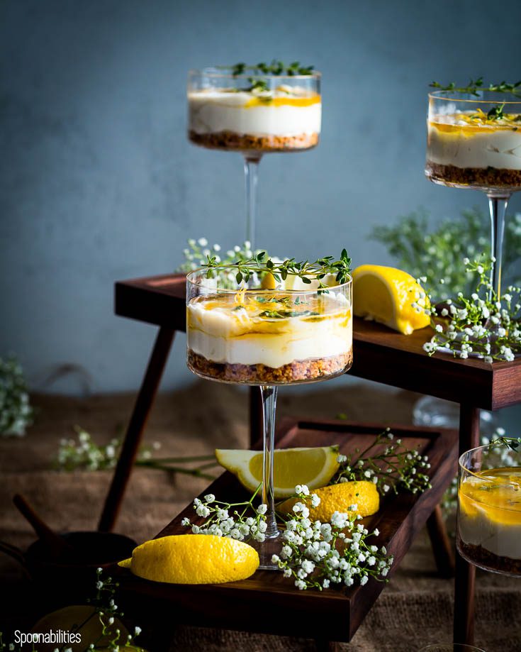 One high rise stand with a cheesecake in a cocktail glass and another high rise stand in the back with two cocktail glasses with the no bake cheesecake. Spoonabilities.com