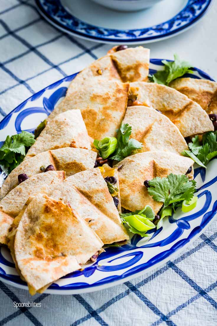 Close up of a oval serving plate with Veggi Quesadillas garnished with scallions & cilantro. Spoonabilities.com