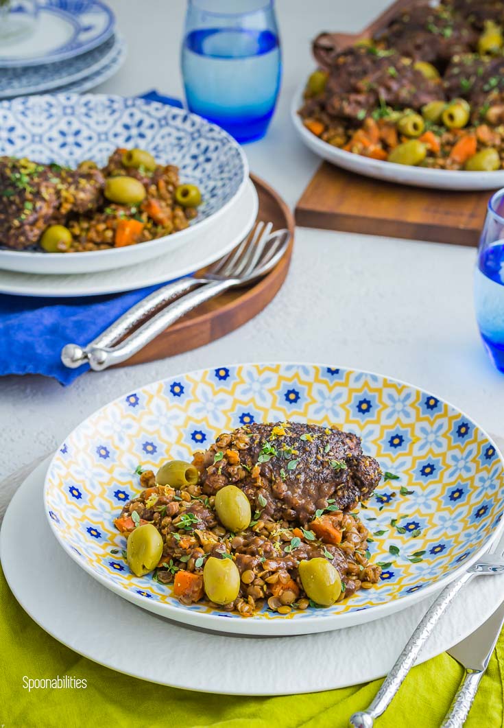 Braised Chicken thighs with lentils & Green Olives in a Pasta Bowl with Greek decor on top of a white plate. Spoonabilities.com