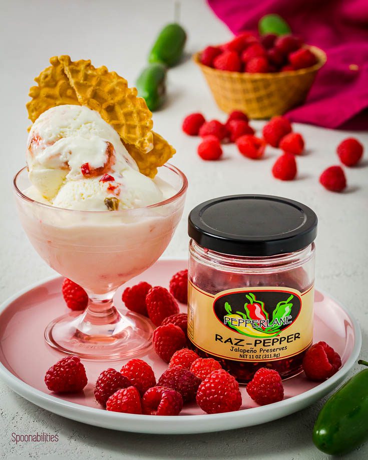 homemade Raspberry jalapeno ice cream in a pink bowl next to the raspberry jalapeno preserve on a pink round plate. Available at Spoonabilities.com