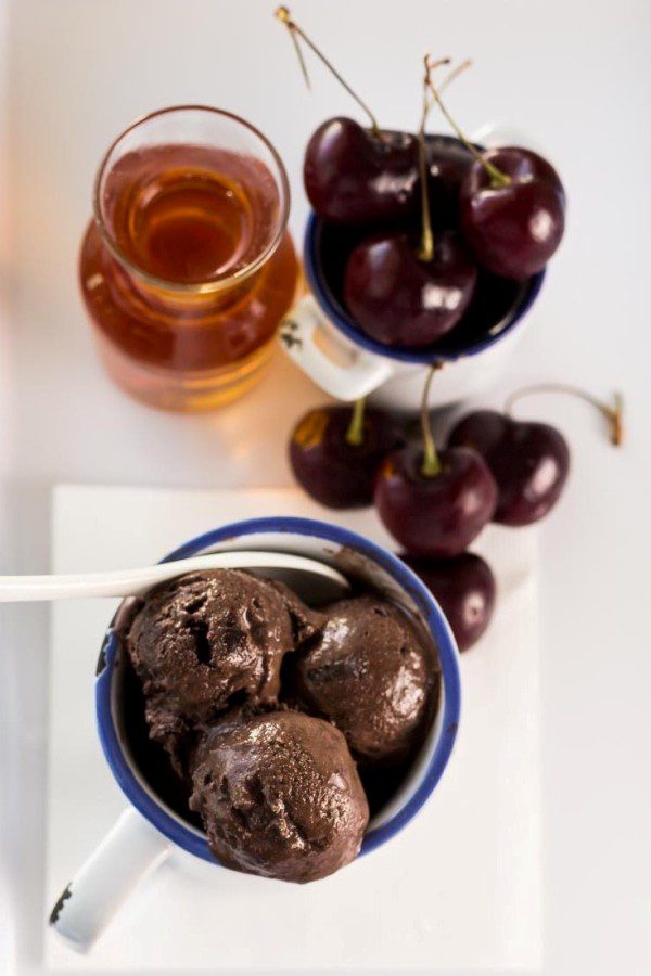 overhead photo of chocolate cherry ice cream, real whole cherries, and glass of brandy