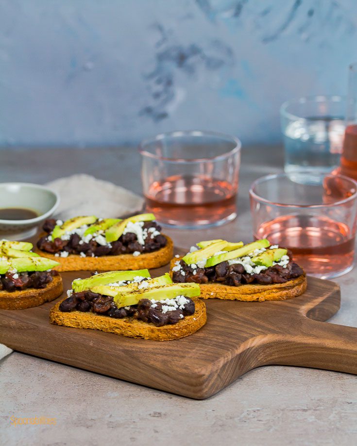 Four Crostini in a wooden board with two glasses of Rose wine. Spoonabilities.com