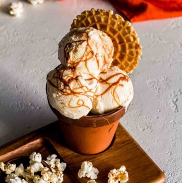 Corn ice cream with Vanilla Goat Milk Caramel Swirl in a terracotta container with popcorn as garnish. Spoonabilities.com