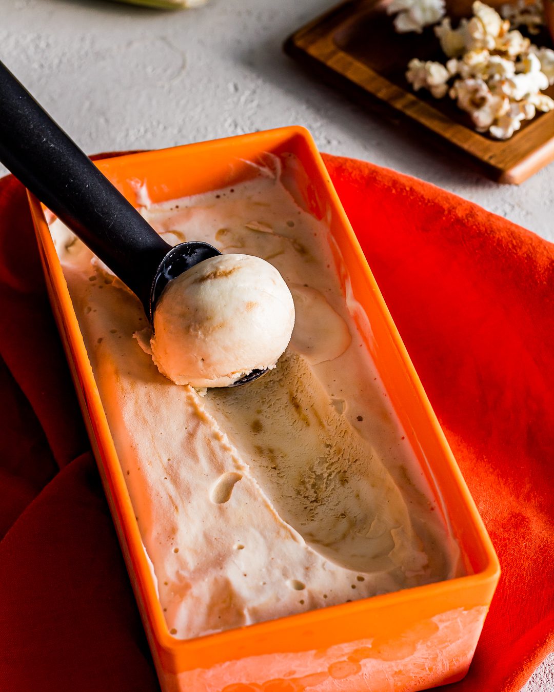 Close up of Caramel ice cream in a orange container with a scoop of ice cream. Spoonabilities.com