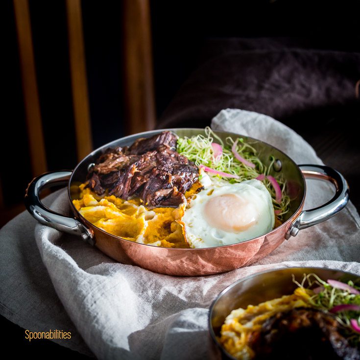 Fall inspired recipes with tender short ribs braised in brandy in the pressure cooker served in a personal cooper fry pan with two handles with Mashed Pumpkin-Cauliflower with brown butter, fried egg, Alfalfa Sprouts & pickled red onions. Spoonabilities.com
