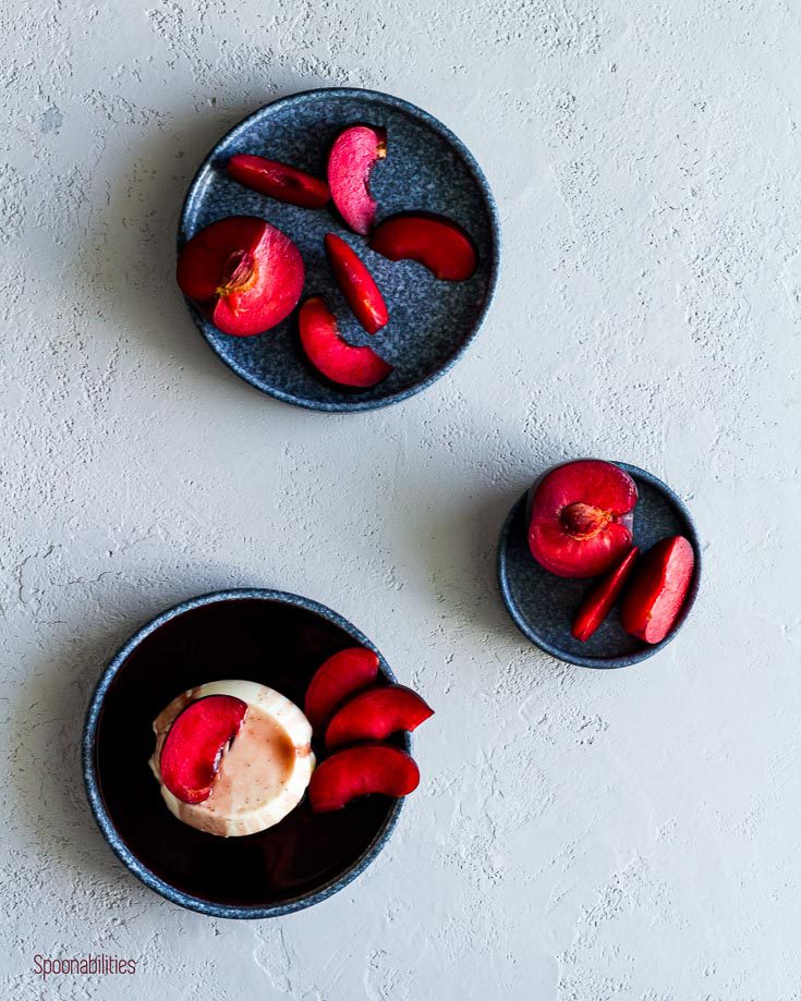 flat lay photo with three blue plate in a zig zag shape. One with panna cotta and the other two with slices of plumcots. Spoonabilities.com