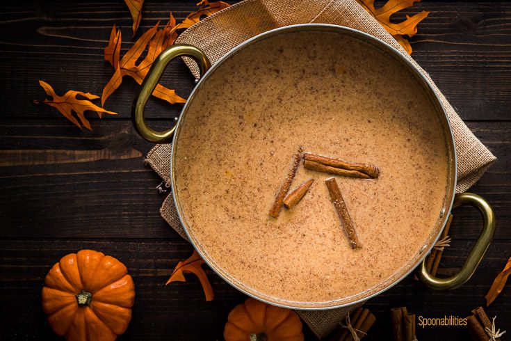 Pot with a mixture of brown butter, cornmeal, whole milk, coconut milk, evaporated milk, pumpkin puree, salt, sugar, & pumpkin spice mix. The scene is decorated with Fall decor. Spoonabilities.com