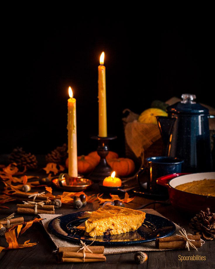 Table decorated with Fall decor with leaves and pumpkin. A blue plate in the center with Arepa Dominicana and in the background candles. Spoonabilities.com