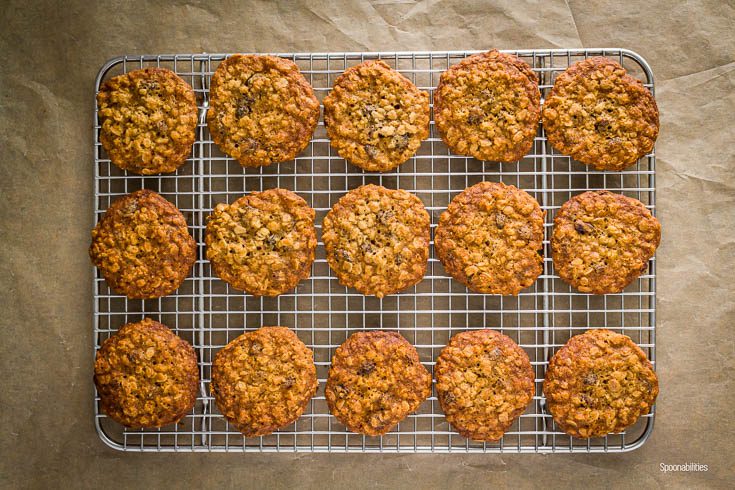 Cooling rack on top of a brown paper with 15 Oatmeal Raisin Maple Bourbon Cookies. Spoonabilities.com